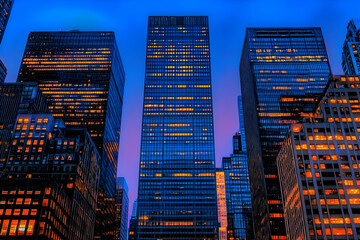 Obraz premium Illuminated Office Towers Shine Brightly Against a Twilight Cityscape with a Modern Architectural Design.