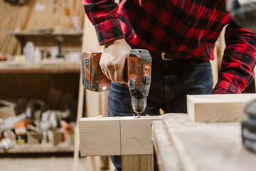 Carpenter Using Drill in Workshop