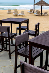 Tropical beachfront bar with empty chairs and tables by the sea