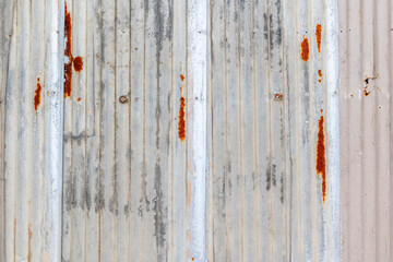 Weathered rusty metal sheet with vertical corrugated texture and patina