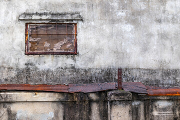 Weathered wall with rusty railing and small window in urban setting