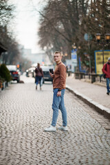 Young man on a cobblestone street holding a coffee cup