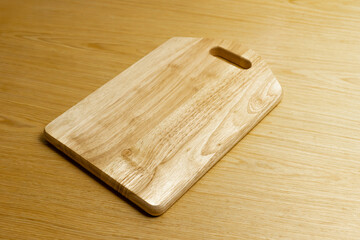 Wooden cutting board on light wood table surface