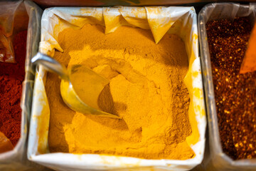 Ground turmeric in a sack with a scoop for gathering it.