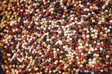 Various types of whole pepper for sale at the market. Black, white, and red peppercorns.