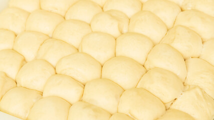 Appetizing balls of yeast dough ready for baking. Warm, soft dough sprinkled with flour creates a cozy home kitchen atmosphere. Perfect for illustrating baking recipes, cooking blogs. 