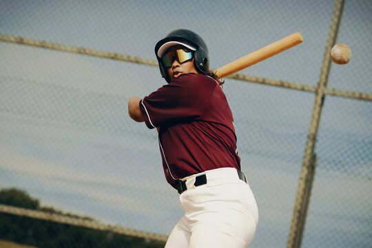 Baseball player mid-swing, preparing to hit the ball during an outdoor game