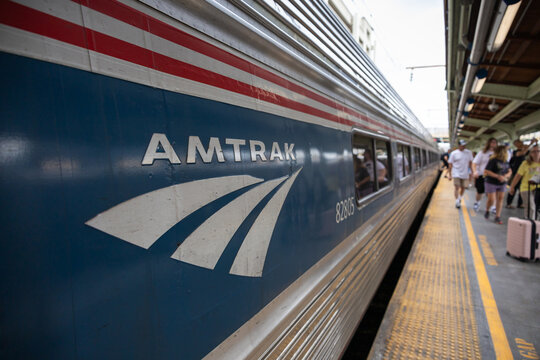 Close-up of an Amtrak train at a busy platform, capturing the logo and passengers boarding in a dynamic urban transportation setting. Train transportation in USA.