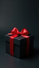 Obraz premium Dark background with a present box that has a red ribbon and bow tied to it with a subtle shadow effect, black,