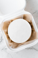 Clean white little bento cake without decoration in a gift box with brown paper inside. Cake mockup with a free space for your own decoration on the white marble background