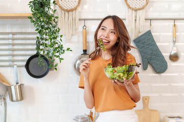 portrait slim asian woman eating vegetables salad,healthy food,vegan,vegetables salad,cooking in the kitchen