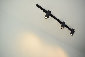 Spotlights under the ceiling on the wall. LED track lighting system. Black interior spotlights