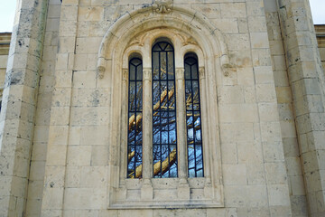 Details of a Mediterranean town: a stone wall with a large arched window, in the glass of which a tree is reflected. Fragment of the Church of St. Michael the Archangel in Herceg Novi, Montenegro
