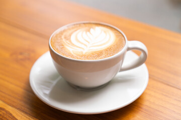 Hot Latte Coffee in a white cup on wooden table background