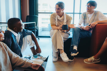 Teacher engaging in conversation with students during a relaxed group discussion in a modern classroom setting