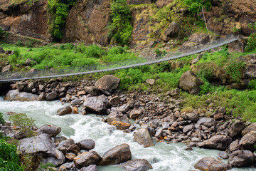 Suspension bridge over Marsyangdi river in Himalaya mountains. Annapurna Circuit Trek. Hiking trekking concept. Beautiful stream. Water in motion. Annapurna Conservation Area, Nepal