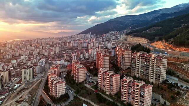 The video shows a multi-story residential construction site. Buildings are at different stages; some in the rough construction phase. The site includes roads, material areas,situated on a hillside.