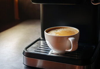 Close-up of espresso pouring from the coffee machine into a coffee cup. Coffee crema