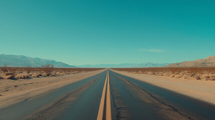Open highway stretching through a desert landscape under a clear blue sky with distant mountains