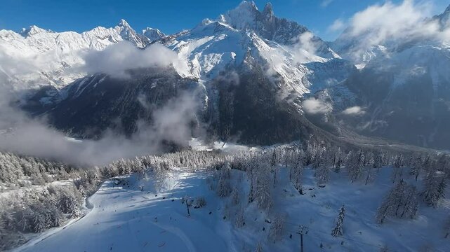 Alpine winter perfection in Chamonix mountain area where dramatic white peaks, frozen valleys, and a bright blue sky create a stunning scene above the clouds. Ski resort close to Mont Blanc, Alpine.