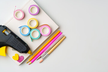 Crafting supplies arranged for creative projects with glue gun, decorative tape, and colorful...