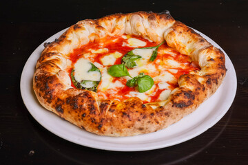 Pizza tradizionale napoletana margherita con sugo di pomodoro, mozzarella e basilico fresco con il cornicione ripieno di ricotta e speck