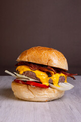 Panino ripieno di hamburger di carne, cheddar fuso, pomodori, insalata e bacon croccante servito in un pub