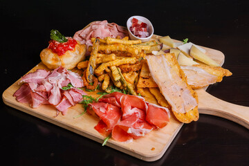 Tagliere di legno con bruschette con lardo, montanara fritta con sugo di pomodoro e basilico, prosciutto crudo, mortadella, prosciutto cotto arrosto e verdure fritte servito come antipasto in un pub