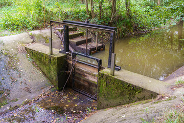 wooden adjustable stop log on a small concrete weir on the canal
