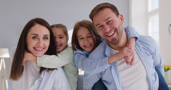 Portrait of a happy family with two kids at home, highlighting affection, parental love, and strong relationships. The bonding and cheerful expressions reflect a nurturing family environment.