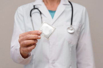 Close up of Doctor hand showing condom wrapper, safe sex and contraception concept