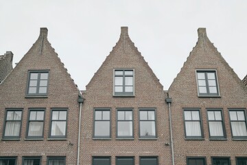 Fototapeta premium Charming brick row houses with gabled roofs line a quiet street under an overcast sky in a small European town during early morning hours