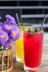 Two glasses with lemonades with ice and mint on wooden table