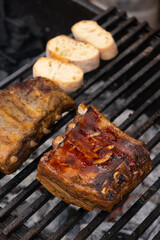 Marinated pork ribs are cooked on the coals of a barbecue
