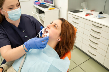 Dentist performing oral examination on patient with mouth retractor in modern clinic