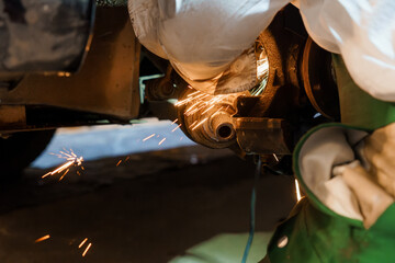 Skilled Mechanic Performing Precision Metal Work with Sparks in Automotive Repair Shop