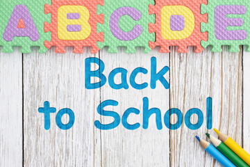 Back to School concept with alphabet foam puzzle and colored pencils