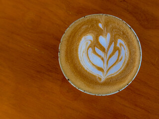 Barista concept, Selective focus of a coffee cup on the table with dark tone, Hot cappuccino or latte art with milk foam on the top, Drinking coffee at the cafe' in the afternoon, Beverage background.