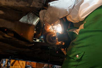 Mechanic Performing Precision Welding Underneath a Vehicle with Sparks Illuminating the Workspace