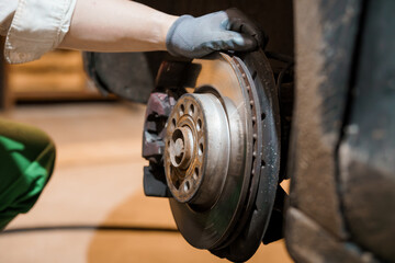 Close-up of a Mechanic Replacing a Car Brake Disc with Gloves on a Workshop Floor © Galka3250