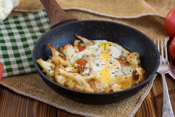 fried omelette with cauliflower and vegetables in a frying pan on a wooden table