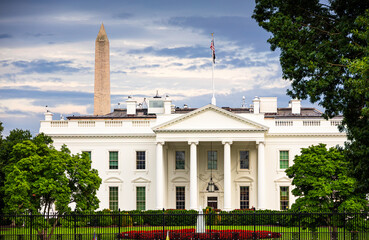 The White House with the Washington Monument in the background, captured on a cloudy day in Washington. A view of iconic American landmarks surrounded by greenery and historical charm. US Presidenct