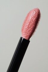 Close-up of a lip gloss applicator with shimmery pink product.