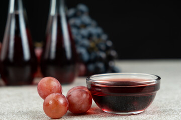 Red wine vinegar in glass vinegar bowls among grapes