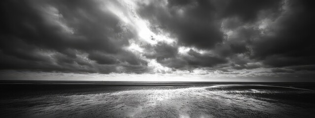 Dramatic black and white sky with dark clouds over a serene ocean landscape creating a moody atmosphere and ample space for text display