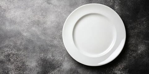 Minimalist white plate on textured gray background with empty space ideal for showcasing gourmet dishes or fine dining concepts.