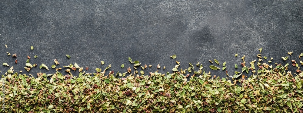 Aufkleber dried shredded oregano on a dark surface with scattered pieces and ample space for text or design el
