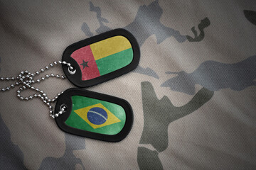 vintage army blank, dog tag with flag of guinea bissau and brazil on the khaki texture background....