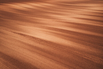 Plowed field on sunny spring day, aerial shot of brown soil with unique unusual pattern from above