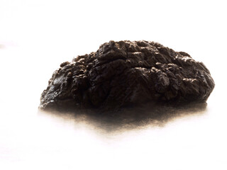 Rocks in the sea crashing against soft waves